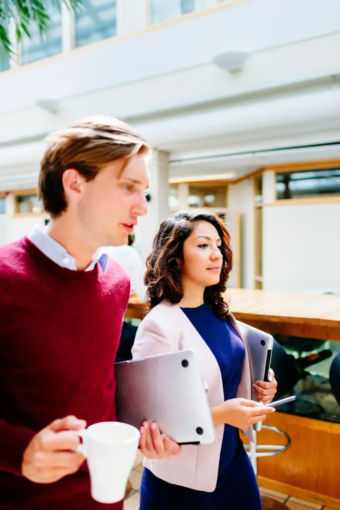 Two colleagues with iPads walking and talking discussing legal consultation for their clients