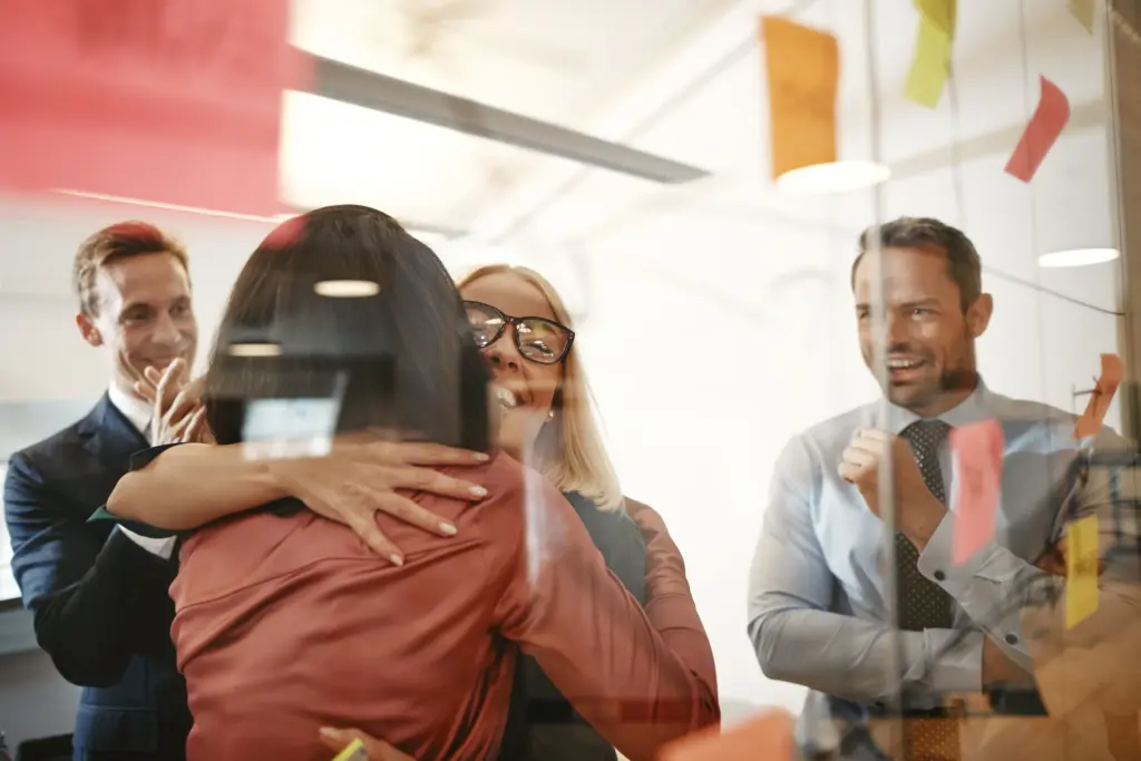 Two women hugging and two men happy after a great win that the Clear Cut Consultants client just had